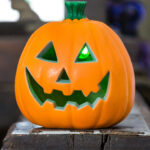 A smiley spooky carved pumpkin sits on a wooden beam in the Fort.