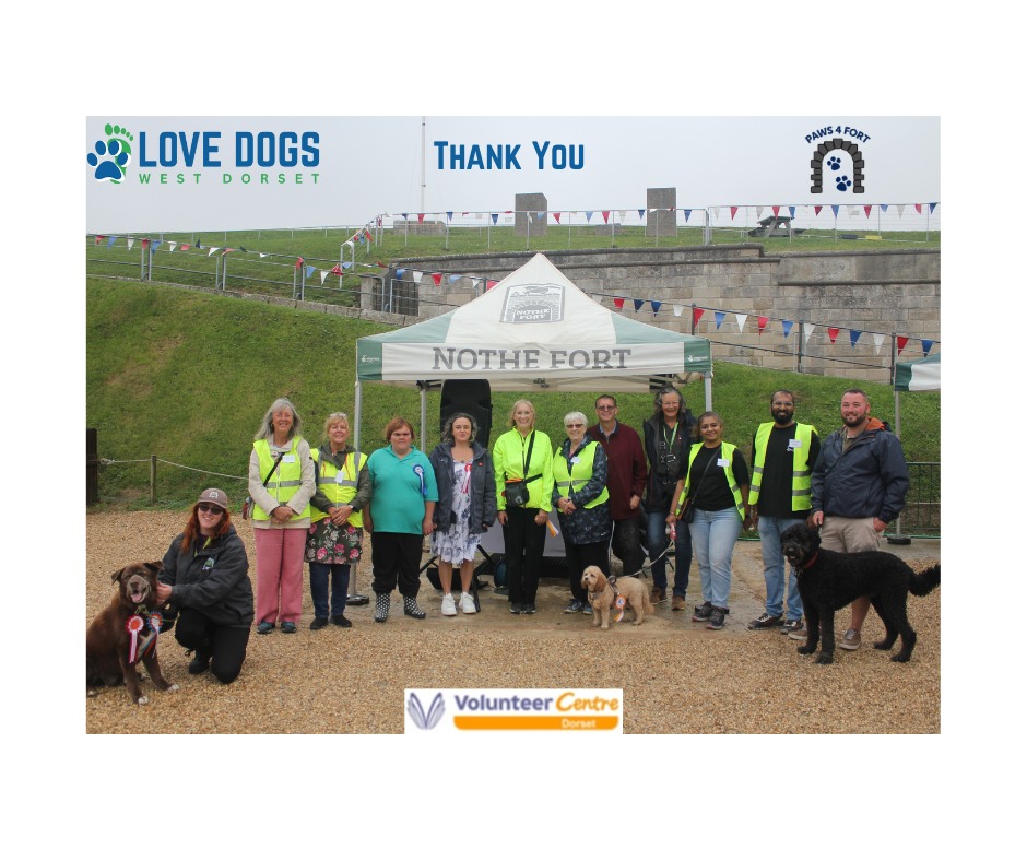 A line up of 12 human volunteers and staff, and three fine dogs represent the Love Dogs West Dorset and Nothe Fort teams. Behind them is a Nothe Fort white and green gazebo, and the walls of the Fort. Above them in blue text reads a thank you message.