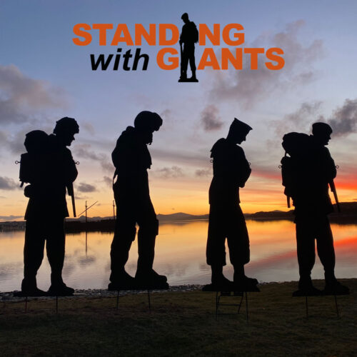 Four metal soldier silhouettes stand against an orange and blue sunset background. The black and orange logo for Standing With Giants is imposed above them on a pale lilac sky.