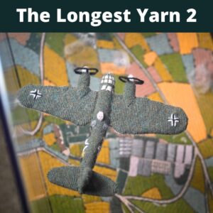A photo of a nitted scene from World War II featuring a german bomber flying over knitted fields.