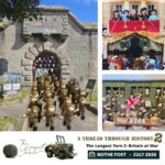 A knitted panel of five rows of WW2 soldiers sits in front of Nothe Fort to demonstrate the exhibition is coming to the Fort. In the background, the grey stone walls of Nothe Fort and the dark archway of the main gate. Above the wall on the ramparts, a heavy artillery gun is visible.