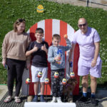 family of four stand in the parade ground in front of an Easter themed coconut shy throwing game.
