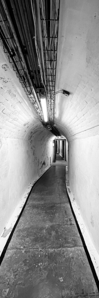A long black and white photo of the curved tunnel to the nuclear bunker.