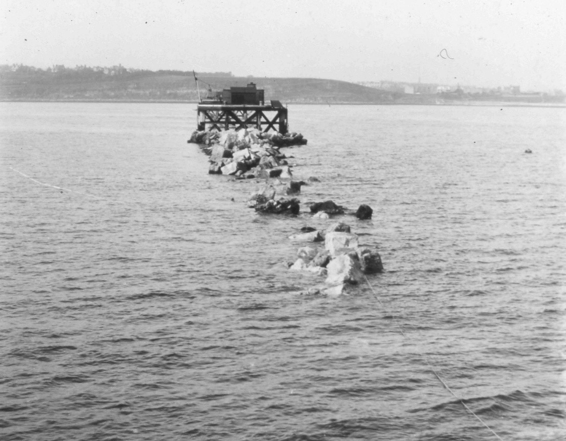 A black and white photo of the Portland breakwater stone barrier surrounded by water.