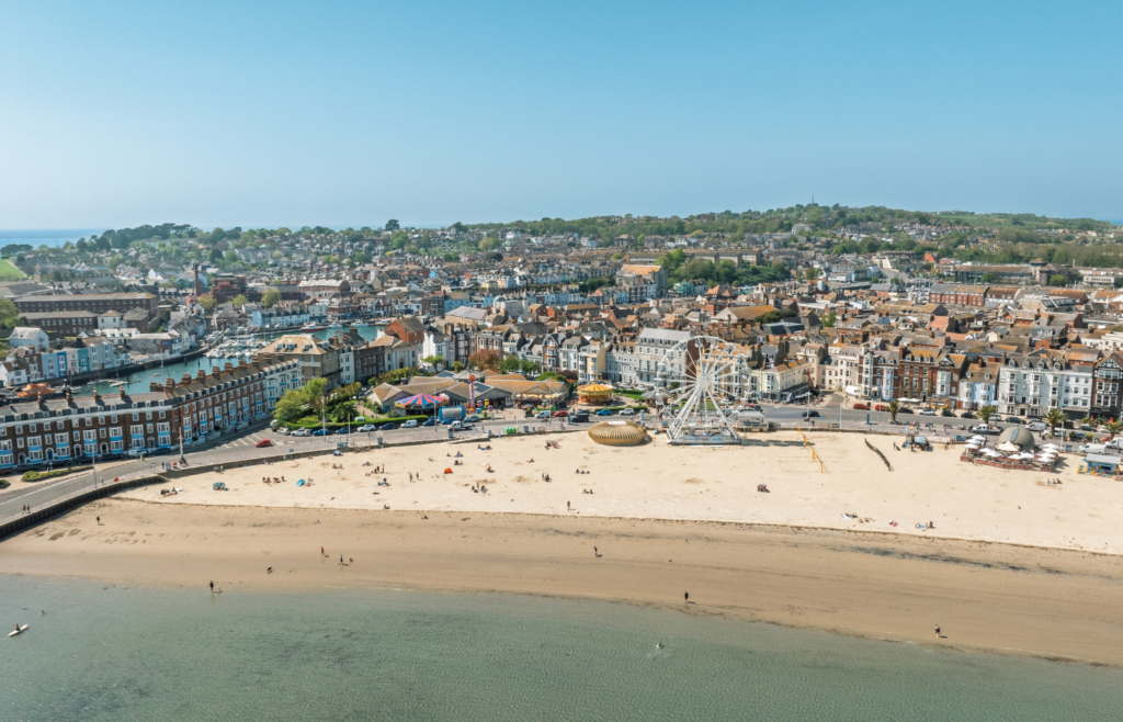 A large landscape drone photo of weymouth beach on a sunny day