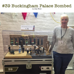 A photo of Jean Wood volunteer behind the impressive knitted panel #39 Buckingham Palace Bombed. 
